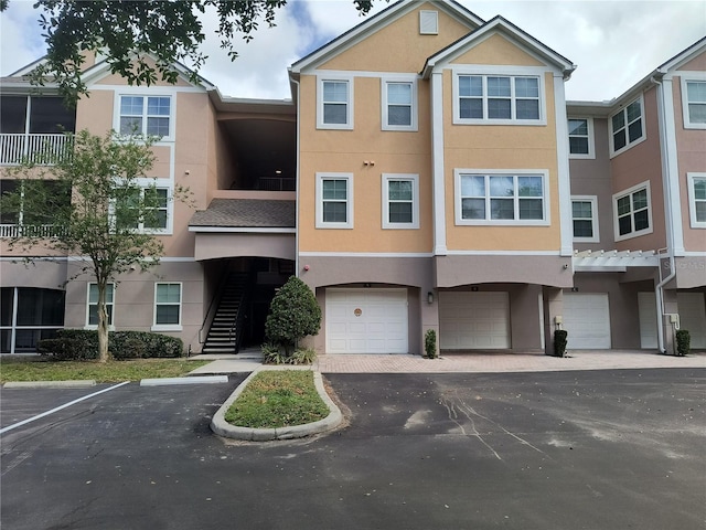 exterior space with driveway, stucco siding, stairway, and an attached garage