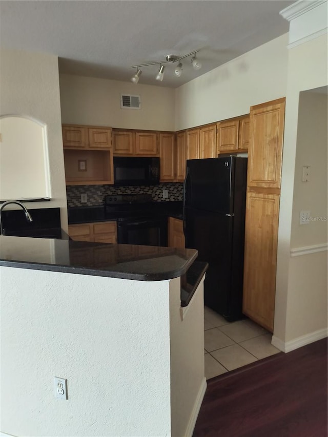 kitchen featuring a sink, visible vents, black appliances, and dark countertops