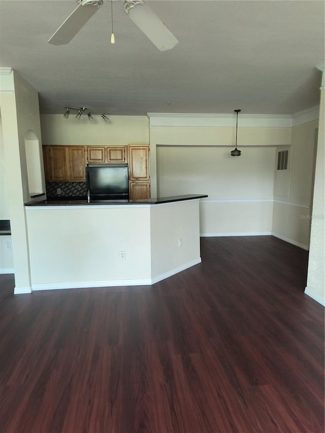 kitchen featuring black fridge, dark wood finished floors, brown cabinets, dark countertops, and ceiling fan