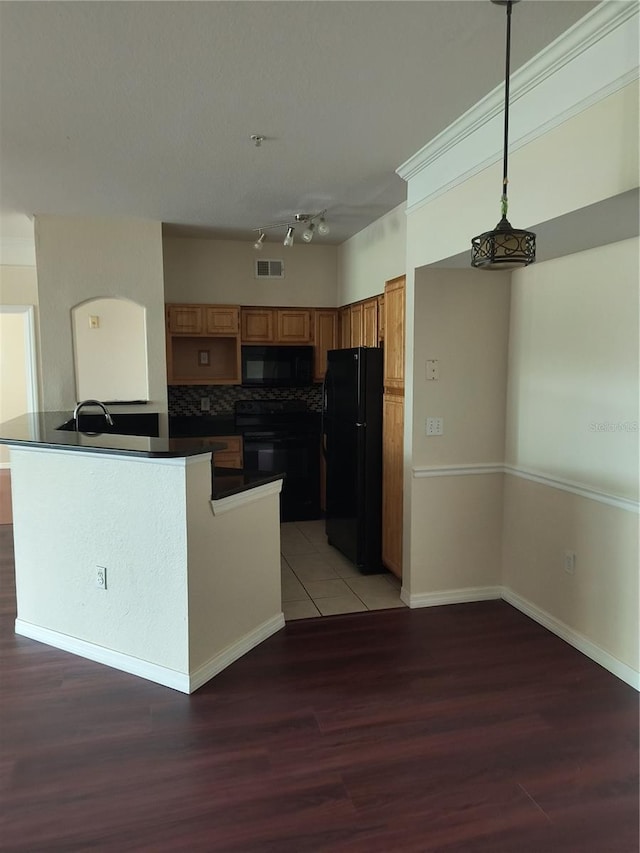 kitchen featuring backsplash, a sink, dark countertops, light wood-style flooring, and black appliances