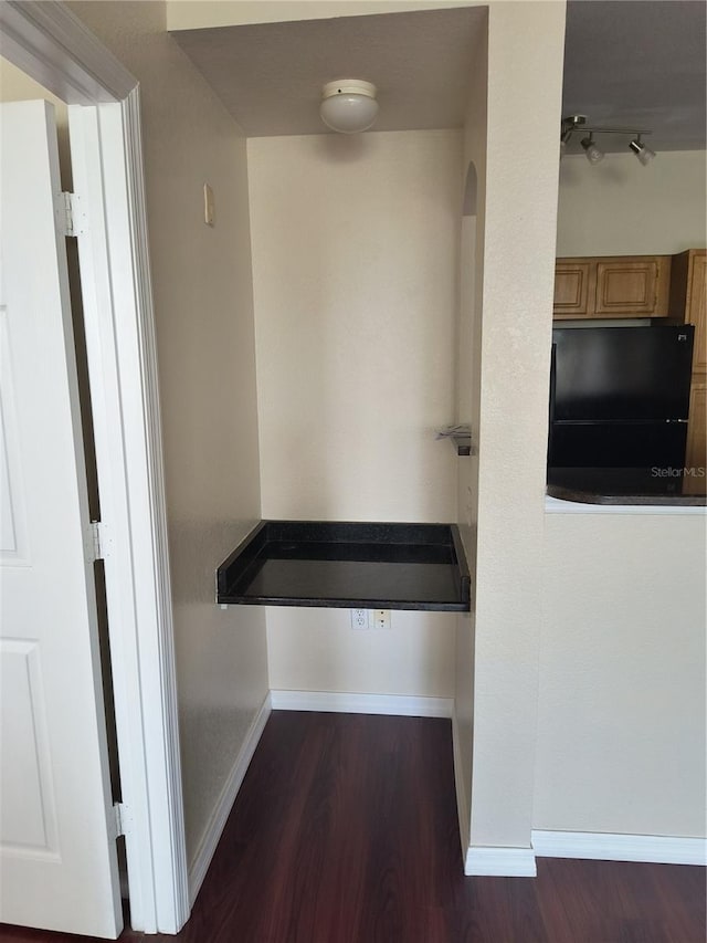 corridor with arched walkways, baseboards, and dark wood finished floors