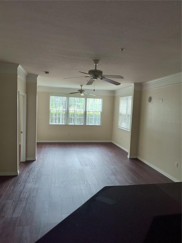 empty room with crown molding, a textured ceiling, dark wood finished floors, baseboards, and ceiling fan