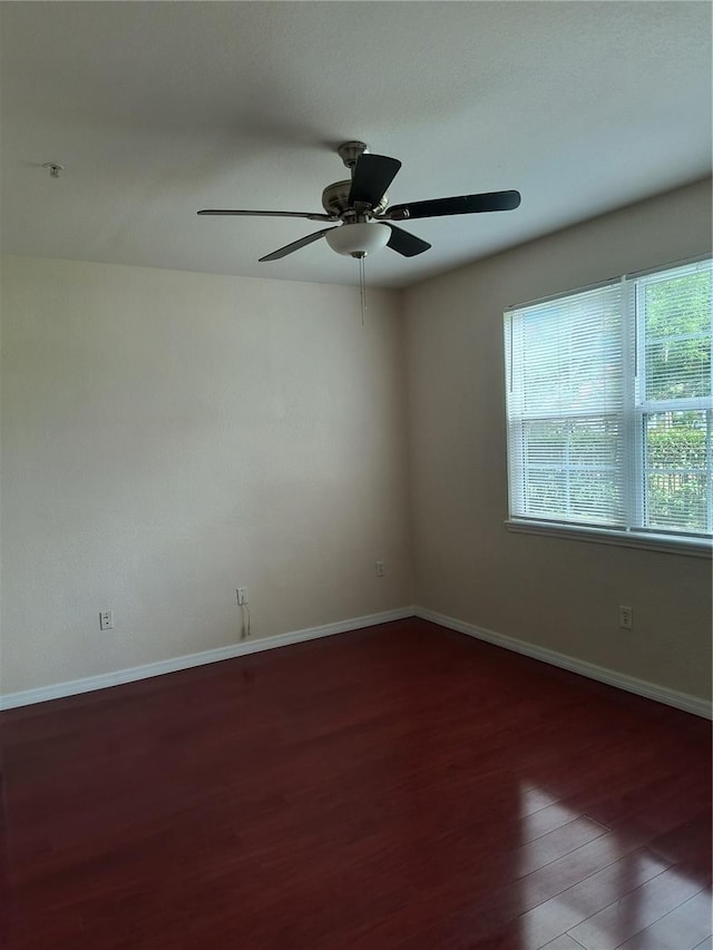 spare room featuring baseboards, wood finished floors, and ceiling fan
