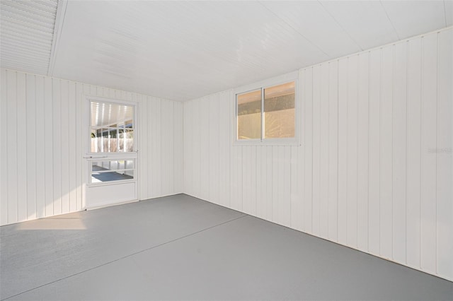 spare room with wood walls and concrete floors