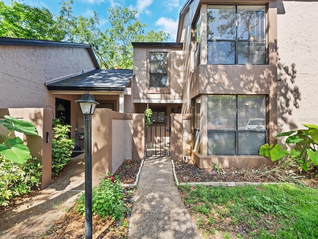 exterior space featuring fence, stucco siding, and a gate