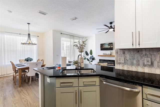 kitchen with stainless steel dishwasher, light wood finished floors, a sink, and visible vents