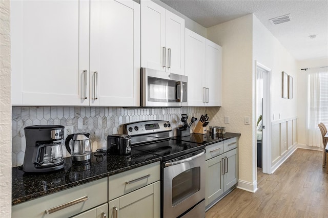 kitchen featuring light wood finished floors, visible vents, decorative backsplash, and stainless steel appliances