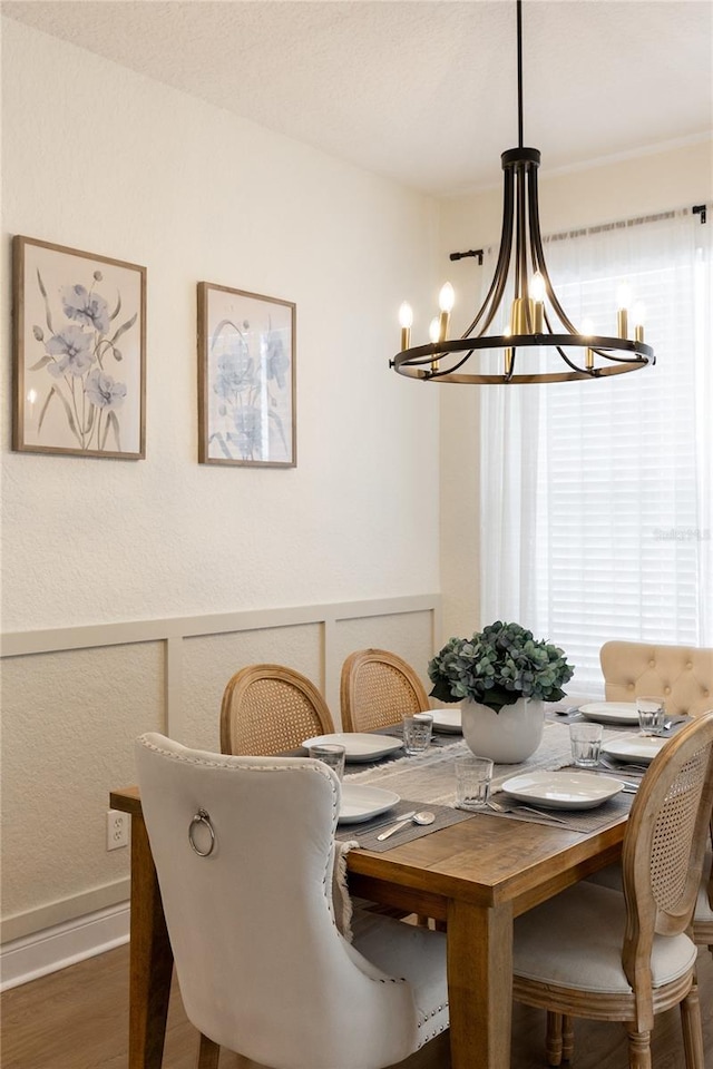 dining space featuring baseboards, wood finished floors, a chandelier, and plenty of natural light