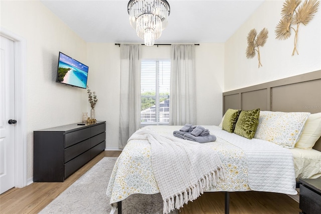 bedroom with baseboards, wood finished floors, and an inviting chandelier