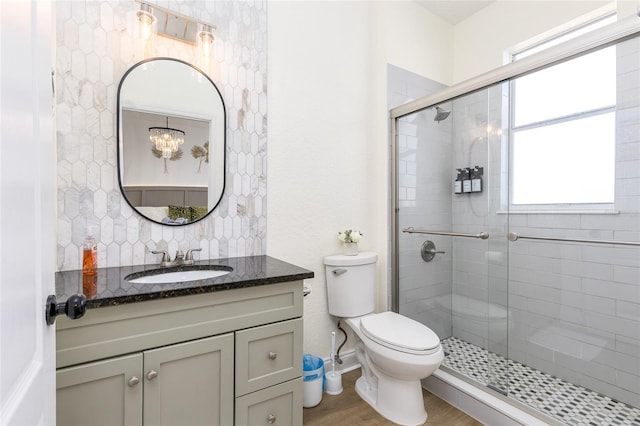 full bathroom featuring tasteful backsplash, toilet, wood finished floors, a shower stall, and vanity