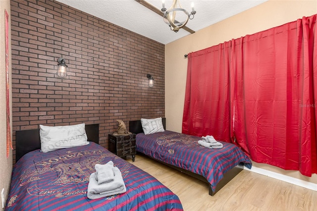 bedroom featuring brick wall, wood finished floors, and a textured ceiling