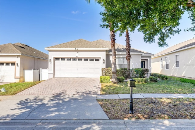 ranch-style house with stucco siding, a front lawn, decorative driveway, and a garage