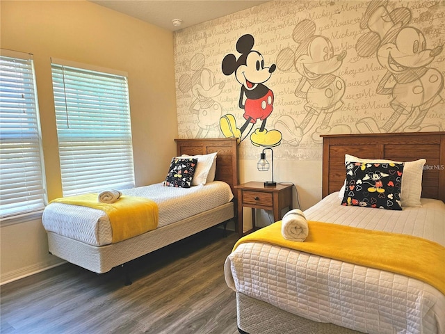 bedroom with baseboards, wallpapered walls, multiple windows, and wood finished floors