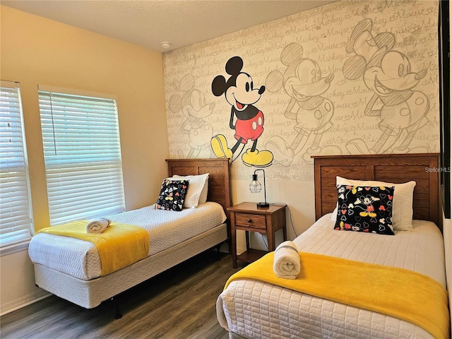 bedroom with baseboards, a textured ceiling, wallpapered walls, and wood finished floors