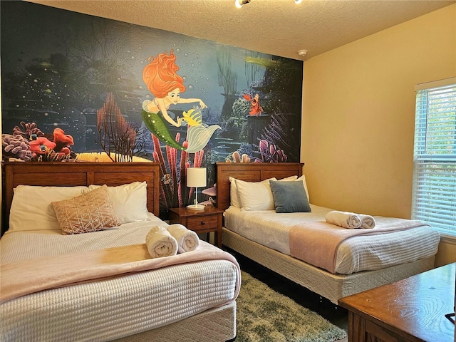 bedroom featuring wallpapered walls, an accent wall, and a textured ceiling