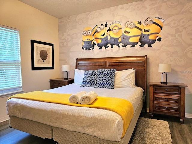 bedroom with baseboards, wallpapered walls, and wood finished floors