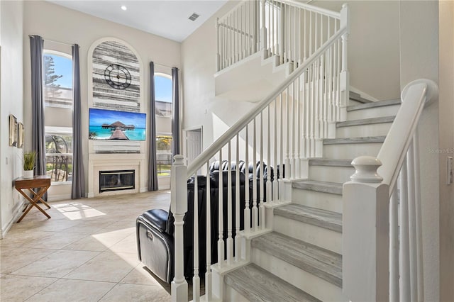 239 Longhirst Loop, Ocoee, FL 34761 - stairs with a high ceiling, a glass covered fireplace, and tile patterned flooring