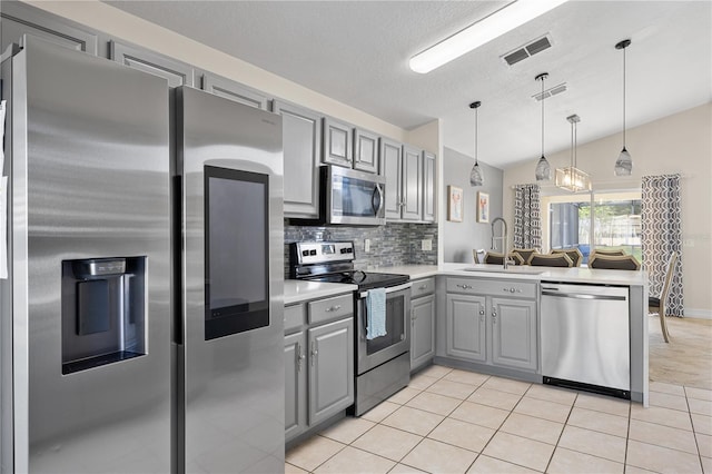 239 Longhirst Loop, Ocoee, FL 34761 - kitchen featuring stainless steel appliances, gray cabinetry, a peninsula, lofted ceiling, and decorative backsplash