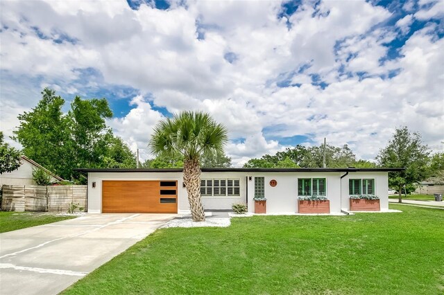 view of front of home featuring stucco siding, a front yard, driveway, and a garage