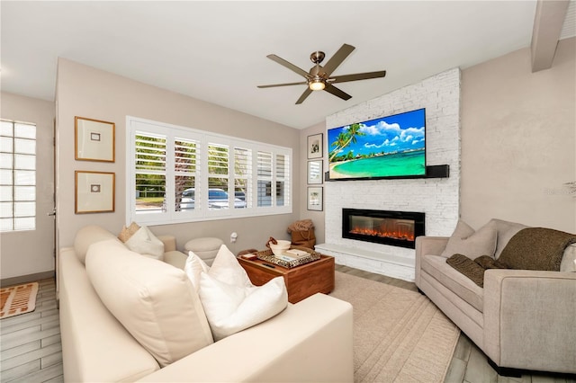 living area with a ceiling fan, a fireplace, and wood finished floors