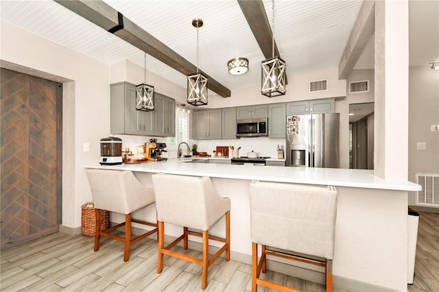 kitchen with a peninsula, stainless steel appliances, gray cabinetry, and visible vents