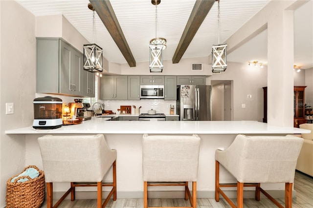 kitchen featuring gray cabinetry, light countertops, stainless steel appliances, and a peninsula