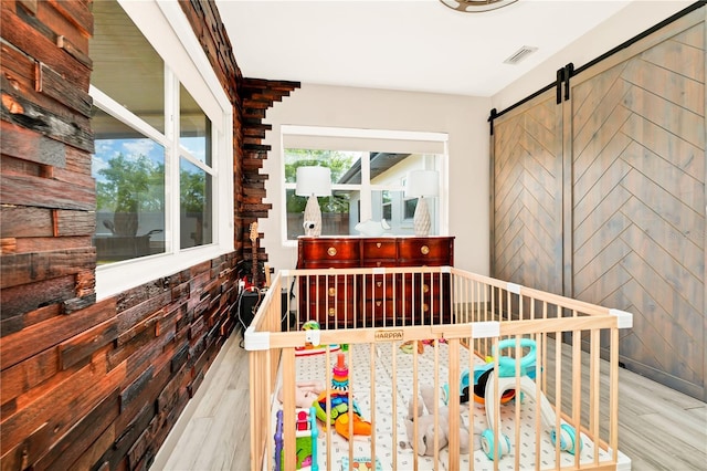 unfurnished bedroom featuring visible vents, a barn door, and wood finished floors