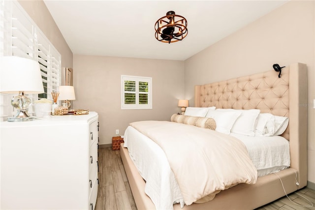 bedroom featuring a notable chandelier, baseboards, and light wood-type flooring