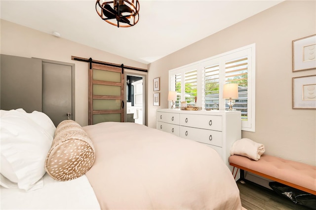 bedroom featuring a barn door and wood finished floors