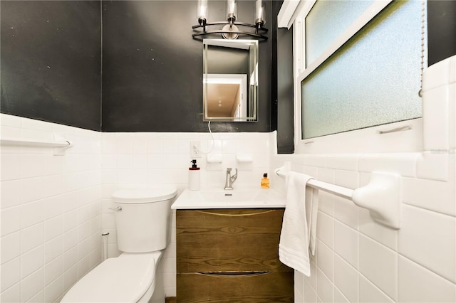 half bath with a wainscoted wall, tile walls, toilet, and vanity
