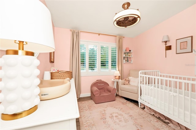 bedroom with baseboards and a nursery area