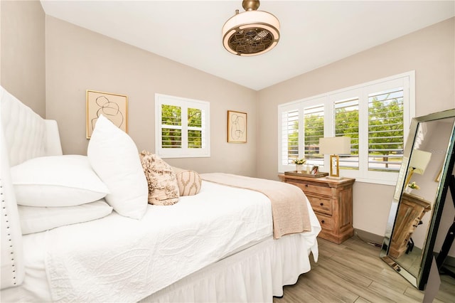 bedroom featuring multiple windows, lofted ceiling, light wood-style flooring, and baseboards