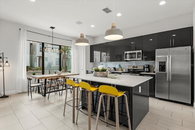 235 Villa Domani Cir, Davenport, FL 33896 - kitchen with appliances with stainless steel finishes, dark cabinetry, light countertops, tasteful backsplash, and decorative light fixtures