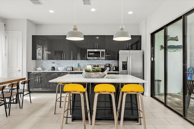 235 Villa Domani Cir, Davenport, FL 33896 - kitchen with stainless steel appliances, dark cabinetry, tasteful backsplash, light countertops, and a breakfast bar