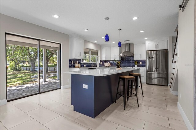 8616 Port Said St, Orlando, FL 32817 - kitchen featuring freestanding refrigerator, wall chimney range hood, white cabinetry, light countertops, and decorative backsplash