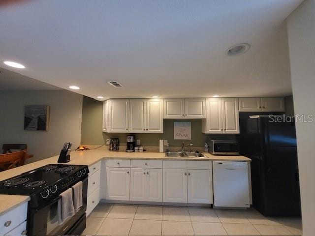 325 N Causeway Unit D104, New Smyrna Beach, FL 32169 - kitchen with light tile patterned flooring, light countertops, white cabinetry, a sink, and black appliances