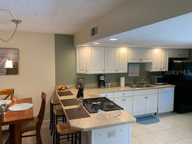 325 N Causeway Unit D104, New Smyrna Beach, FL 32169 - kitchen featuring white cabinetry, light countertops, visible vents, a peninsula, and black appliances