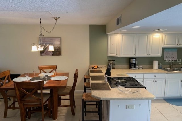 325 N Causeway Unit D104, New Smyrna Beach, FL 32169 - kitchen featuring light countertops, visible vents, a peninsula, white cabinetry, and a sink