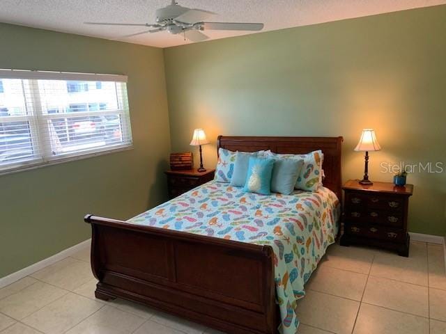 325 N Causeway Unit D104, New Smyrna Beach, FL 32169 - bedroom with baseboards, a ceiling fan, light tile patterned floors, and a textured ceiling