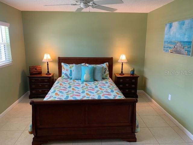 325 N Causeway Unit D104, New Smyrna Beach, FL 32169 - bedroom featuring light tile patterned flooring, baseboards, ceiling fan, and a textured ceiling