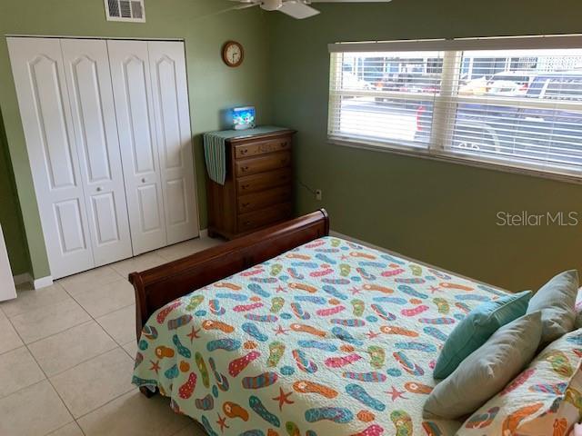 325 N Causeway Unit D104, New Smyrna Beach, FL 32169 - bedroom featuring light tile patterned flooring, visible vents, a closet, and ceiling fan