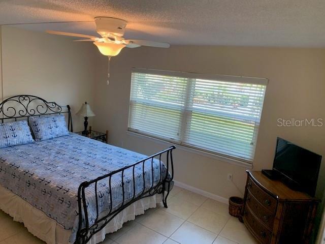 325 N Causeway Unit D104, New Smyrna Beach, FL 32169 - bedroom with light tile patterned flooring, baseboards, ceiling fan, and a textured ceiling