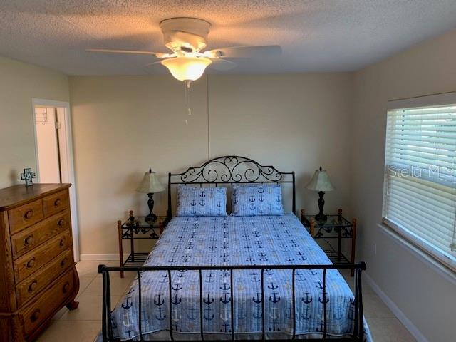 325 N Causeway Unit D104, New Smyrna Beach, FL 32169 - bedroom featuring light tile patterned flooring, a textured ceiling, and baseboards