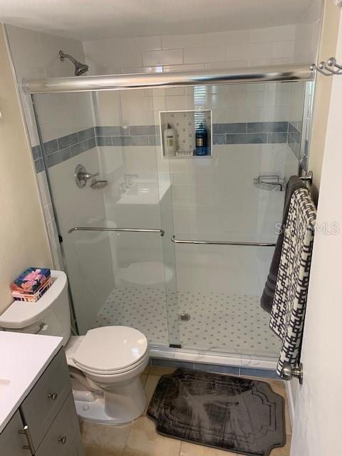 325 N Causeway Unit D104, New Smyrna Beach, FL 32169 - bathroom with a shower stall, tile patterned floors, toilet, and vanity