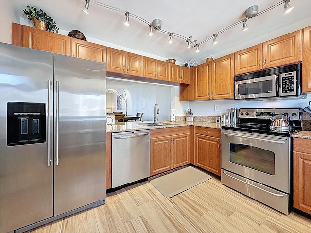 1581 Gulf Blvd Unit 102N, Clearwater Beach, FL 33767 - kitchen featuring stainless steel appliances, a sink, brown cabinetry, light stone countertops, and light wood-style floors