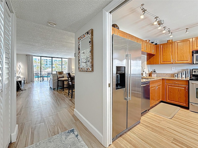 1581 Gulf Blvd Unit 102N, Clearwater Beach, FL 33767 - kitchen featuring appliances with stainless steel finishes, a sink, light wood-style flooring, baseboards, and a textured ceiling