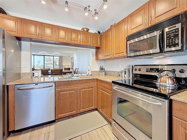 1581 Gulf Blvd Unit 102N, Clearwater Beach, FL 33767 - kitchen with appliances with stainless steel finishes, light stone countertops, brown cabinetry, and a sink