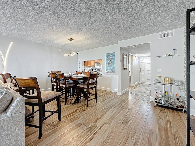 1581 Gulf Blvd Unit 102N, Clearwater Beach, FL 33767 - dining area featuring light wood-style flooring, a textured ceiling, baseboards, and a chandelier