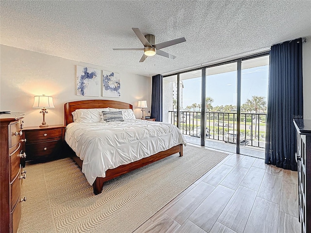 1581 Gulf Blvd Unit 102N, Clearwater Beach, FL 33767 - bedroom featuring expansive windows, access to outside, a textured ceiling, ceiling fan, and light wood-type flooring