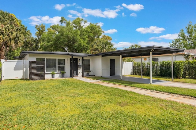 view of front of property featuring a front yard, an attached carport, concrete driveway, and fence
